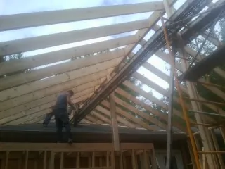 Rafters going up over a new addition with a worker on the wall in Princeton
