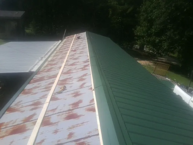 Old rusted panels beside newly installed green metal roofing — Wind Damage Roof Repair by Roofing Brothers in Princeton